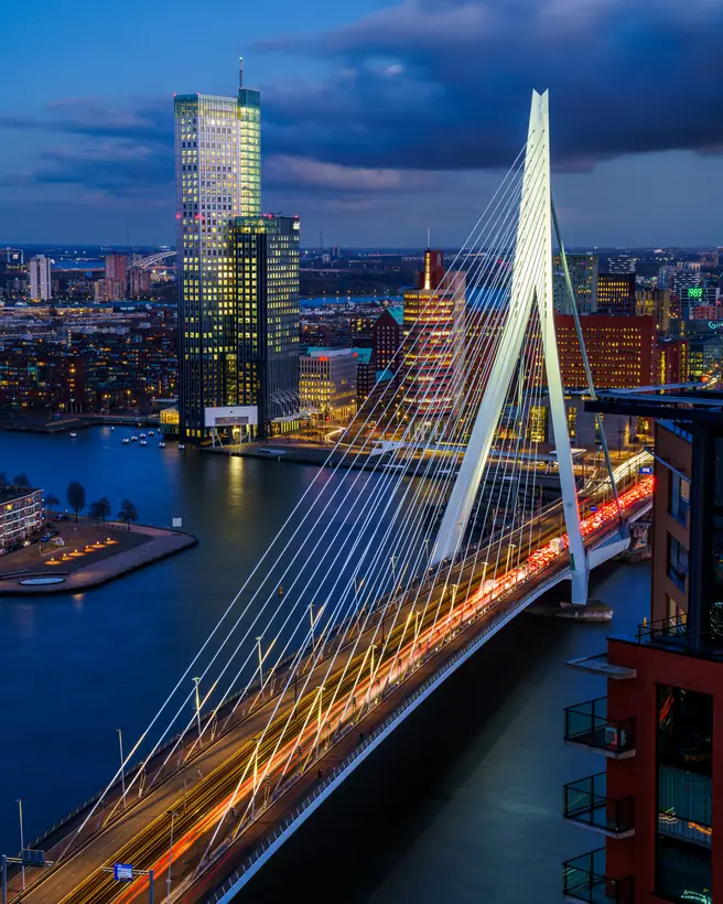 De Erasmusbrug vanaf een dak tijdens het blauwe uur met lichtsporen
